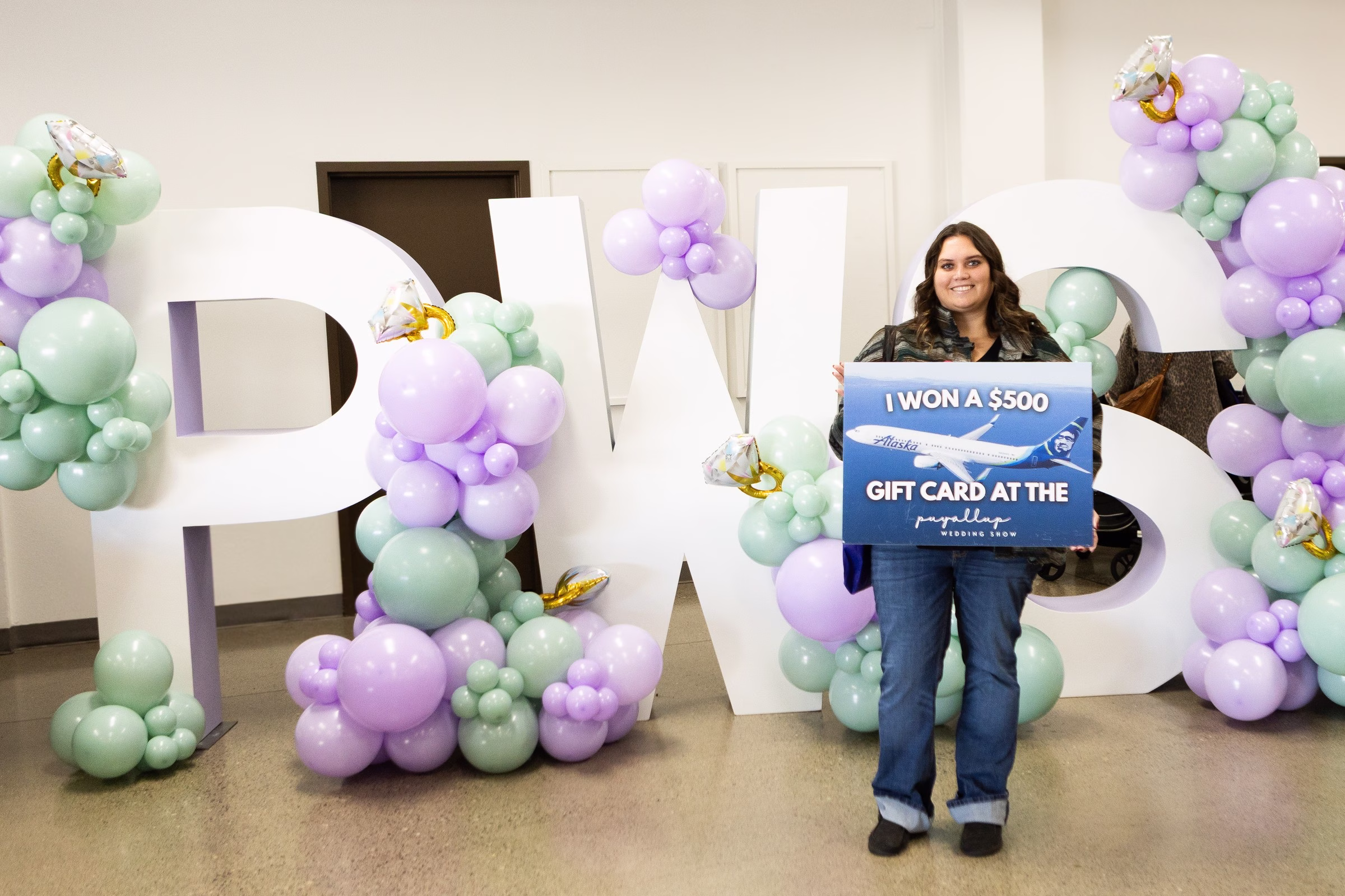 puyallup wedding show alaska airlines 500 gift card winner - February 2027 A happy winner holds an Alaska Airlines 500 dollar gift card prize sign in front of large PWS balloon letters at the Puyallup Wedding Show in Puyallup Washington