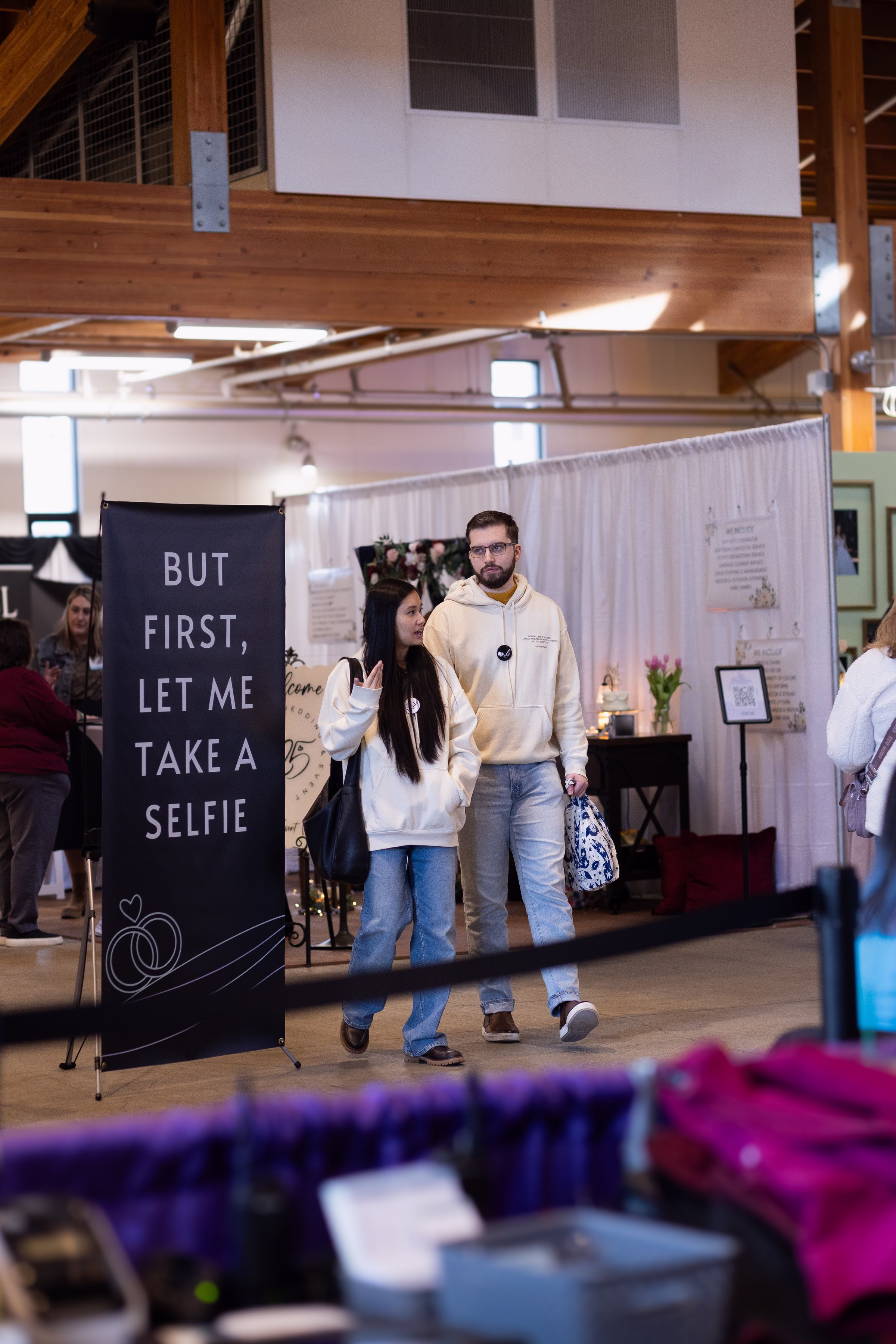 puyallup wedding show bridal expo couple browsing - The Puyallup Wedding Show A couple walks past a but first let me take a selfie banner at the Puyallup Wedding Show bridal expo in Puyallup Washington