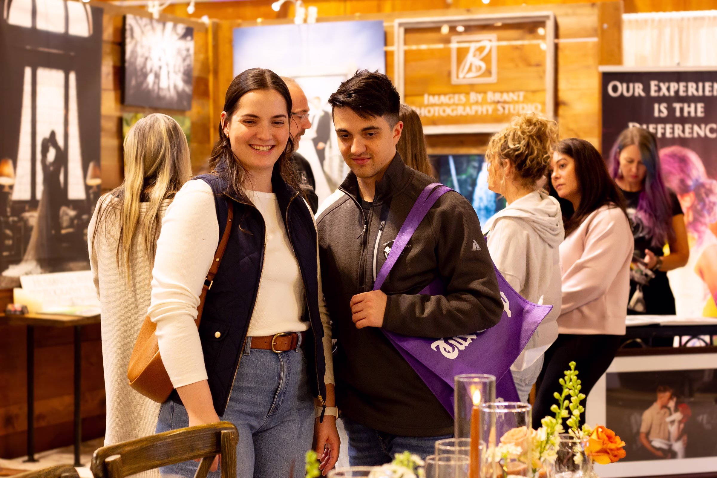 puyallup wedding show bridal expo couple photography vendor - Exhibiting Information A smiling couple browses vendor booths at the Puyallup Wedding Show bridal expo in Puyallup Washington, with Images by Brant Photography Studio visible in the background