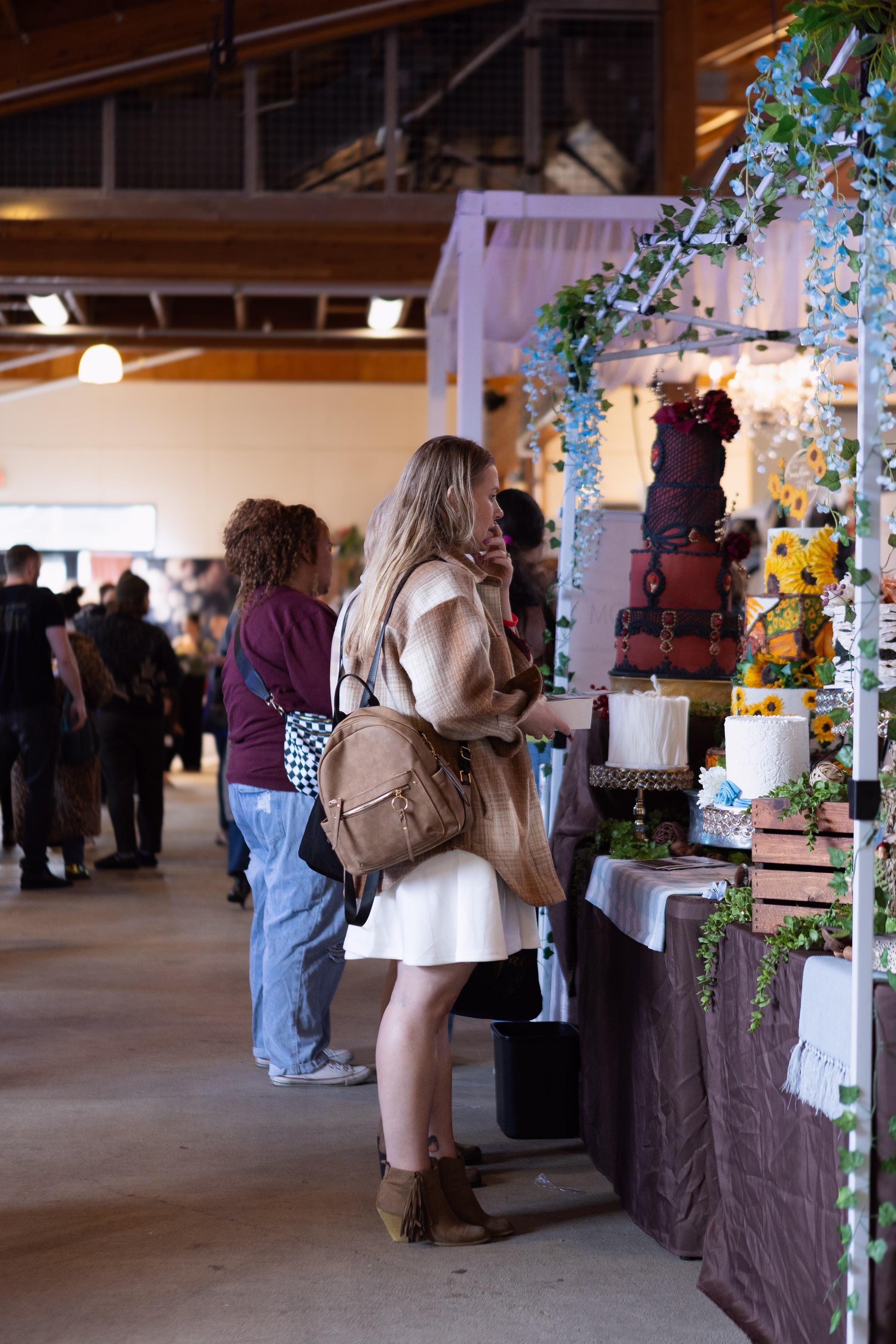 puyallup wedding show cake display bridal - Exhibiting Information Guests browsing an elaborate wedding cake display with floral decor at the Puyallup Wedding Show bridal expo in Puyallup Washington