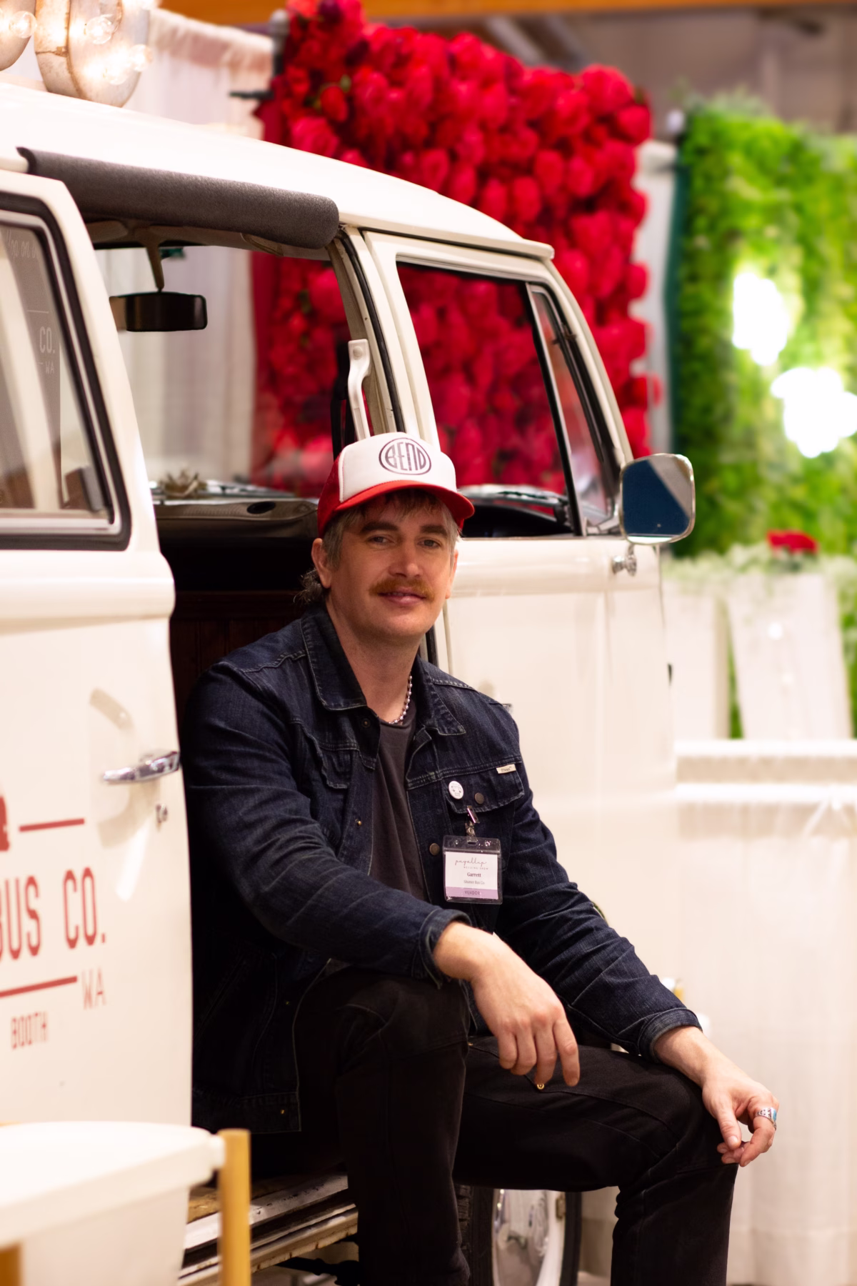 puyallup wedding show vendor booth vintage van roses - Exhibiting Information A vendor representative sits in front of a white vintage Volkswagen van decorated with a wall of red roses at the Puyallup Wedding Show in Puyallup Washington